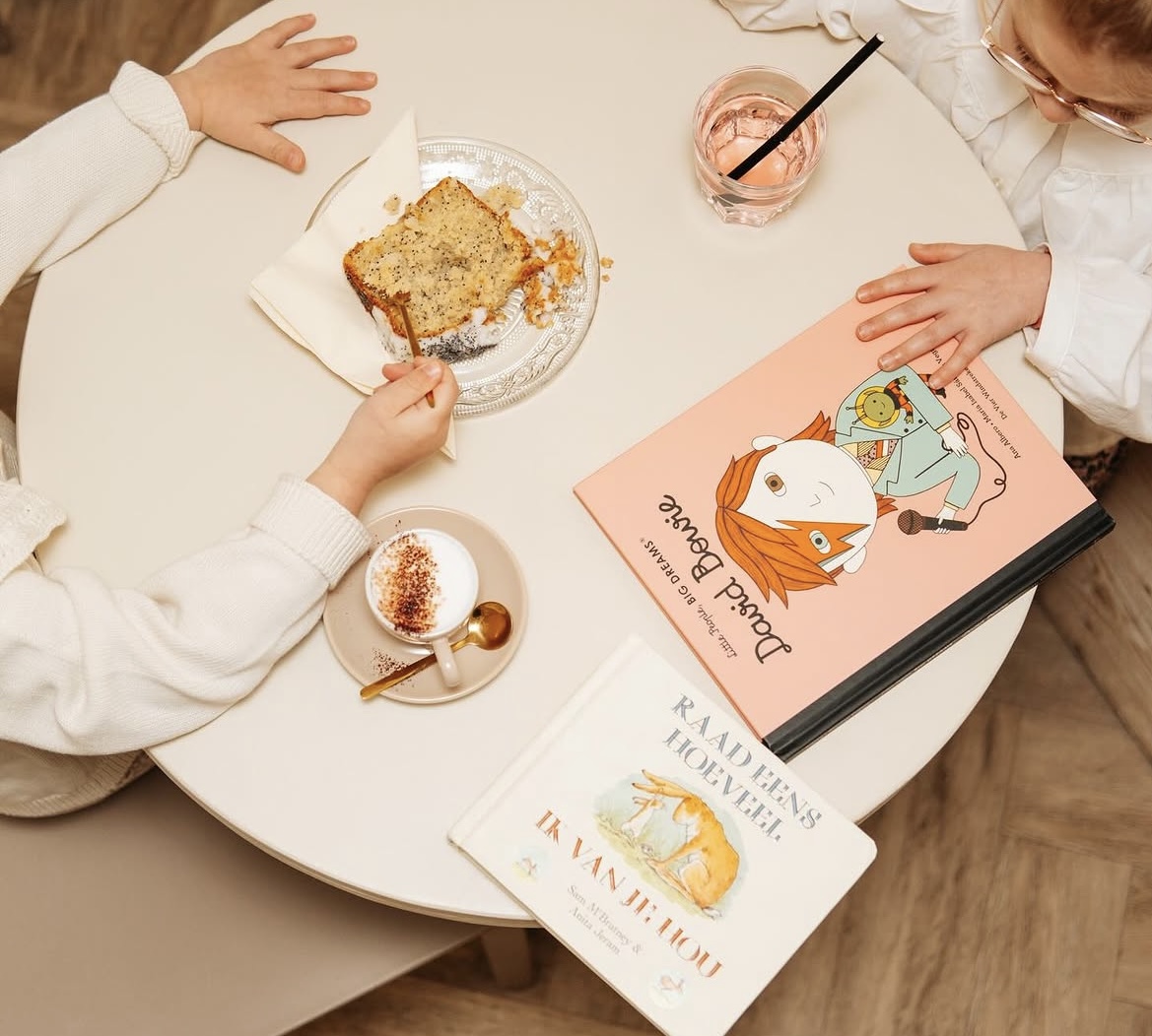 Kinderen aan tafel met cake, koffie en prentenboeken