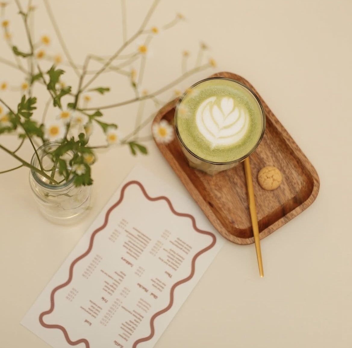 Matcha latte met bloemen en een houten dienblad