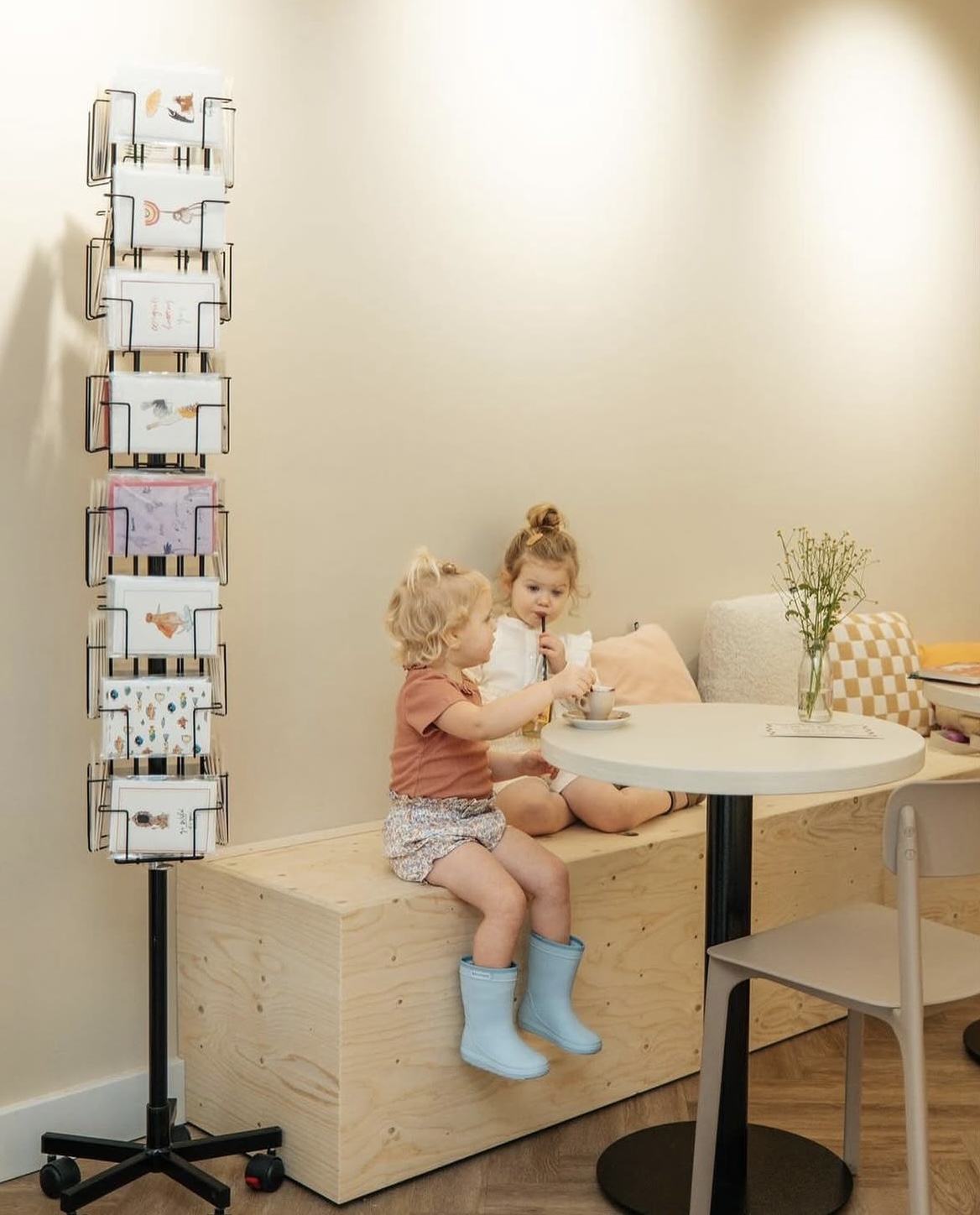 Twee kinderen op de houten bank bij de kaartenrek